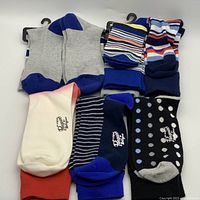 All pairs of assorted men's socks laid out, showing varied colors, patterns, and Penguin branding on some.