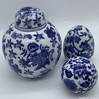 Blue and white ceramic ginger jar vase with lid along with decorative egg and orb, all featuring blue floral patterns on white ceramic.