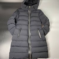 Full front view of black puffer coat laid flat
