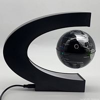 Front view of the C-shaped black frame with magnetic globe levitating in the center, powered by USB cable.