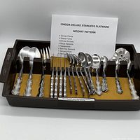 Photo of the full flatware set arranged in a tray with a description sheet.