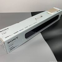 Box of Sony HT-S100F sound bar showing model number and features including 120W power, HDMI, Bluetooth, USB.