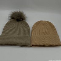 Lot image showing two knit beanies side by side, one with a pompom and one without.