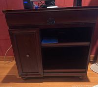 Front view of the desk showing pull-out keyboard tray, cabinet door with knob, and open shelves