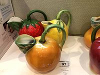 Photo showing the three pitchers shaped and painted as strawberry, lemon, and orange with leafy details, placed side by side.