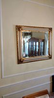 Full view of ornate mirror hanging on wall, showing overall size and reflective quality