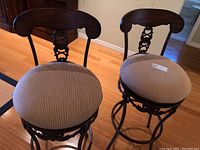 View showing both bar stools with wood backrests, wrought iron frames, and upholstered seats.