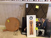 View showing Linkin Park poster, giraffe clock, velveteen wall hanging, wrought iron plant holder, and composite wood side table grouped on floor.