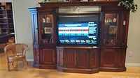 Front view of the entire entertainment center fully assembled with a TV inside the middle unit.