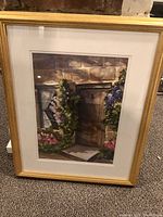 Framed watercolour painting depicting a stone entrance with surrounding flowers in a gold frame.