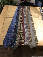 Display of multiple silk ties laid out on a wooden surface showing assorted colors and patterns.