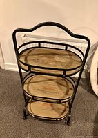 Full view of three-tier iron frame shelf with wooden shelves showing overall structure and wear.