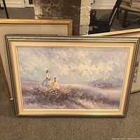 Full view of the framed seaside landscape painting featuring two women in vintage dresses by the sea, with distant mountains and sailing boats.