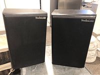 Front view of the pair of black StudioLAB speakers with fabric grille and logo.