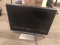 Front view of Toshiba flat screen TV on silver stand, showing the black screen and frame with brand markings.