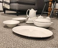 View of all serving pieces including platter, two bowls, covered serving dish, gravy boat, creamer, and sugar bowl arranged on carpeted floor.