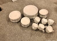 Full set of 50 pieces arranged on carpet: 10 dinner plates, 10 lunch plates, 10 bread plates, 10 cups, and 10 saucers.