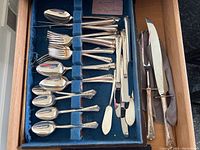 Tray of silver plate spoons, forks, butter knives, and serving knives in blue felt lined drawer