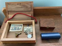 Contents inside a wooden display box with glass top including photos, tie clips, pocket watch and compass