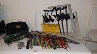 Overview of tools arranged showing quick grip clamps standing upright, various hand tools and measuring tools laid flat, and the black canvas tool bag.