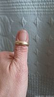 Ring displayed on thumb against quilted background showing overall appearance
