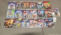 Overview of nineteen PS3 video games in cases laid out on a table.