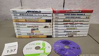 Front view showing complete set of 22 Wii game cases stacked together alongside two Wii game discs.