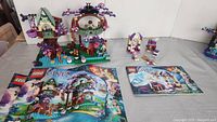 Two LEGO Elves sets displayed with instruction manuals in front of them. Larger treehouse build on the left, smaller set on the right.