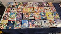 Top view showing 36 anime DVD cases arranged in rows, covers feature various anime characters and titles such as Howl's Moving Castle and Sailor Moon.