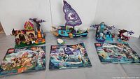Three assembled LEGO Elves sets on display alongside their instruction booklets.