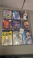 Photo shows nine PlayStation 2 video game cases arranged in rows of three. Titles and cover arts are visible including RPG Maker II, Persona 3 FES, Manhunt, Siren, Unreal Tournament, Mystic Melee, Gun, Prince of Persia, and Death by Degrees.