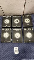 Photo of Death Note Black Edition volumes 1 to 6 laid out on a blue surface in two rows.
