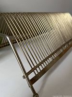 Close-up of the brass-tone wire frame structure showing the curved design and spaced vertical bars.