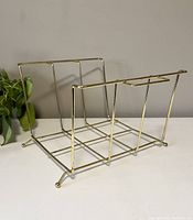 Side angled view showing metal frame and design of vintage brass-toned magazine rack.