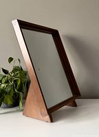 Side view of the wooden framed mirror showing its angled wooden support legs and mirror surface.