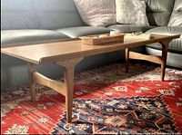 Full view of wooden surfboard coffee table on patterned rug