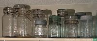 Shelf with ten antique canning jars, various brands and closure types