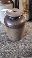Side view of antique pottery butter churn showing entire body and wooden lid with hole