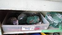 Shelf with plastic bin holding glass and mineral specimens plus two large aqua glass chunks beside it