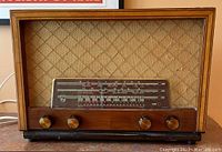 Front overview of the vintage Philips tube radio showing wooden cabinet, fabric grill, frequency dial, and four control knobs.