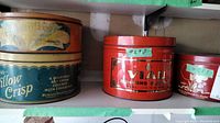 Four vintage cookie/confectionery tins arranged on shelves, showing brand names and wear.