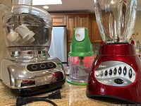 KitchenAid food processor, red Oster blender, and green Ninja mini chopper on countertop