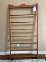 Front photo of the wooden quilt and blanket display rack showing six horizontal dowels and the decorative top edge.