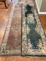 Two floral wool rug runners laid out flat on hardwood floor showing full length and designs.