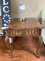 Vintage Drexel wood side table with curved legs, drawer, and detailed wood grain top surface.