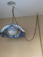 Side view showing the hanging stained glass lamp with extended chain attached to ceiling.