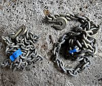 Both chains coiled on concrete floor with clevis hooks visible, showing general condition and size.