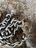 Close-up photo of one chain's clevis hook and metal links on a concrete floor.