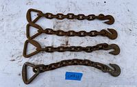 Four 3/8 inch chain extenders laid out side by side on a white fabric surface, each with triangle handles and hooks on opposite ends. Visible surface rust and wear on metal.