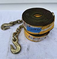 Rolled yellow winch straps with attached chain hook visible, photographed on white surface.